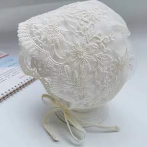 Detail of white lace baby bonnet with floral embroidery and ruffle trim for photography