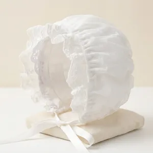 Detail of white lace baby bonnet with floral embroidery and silk ribbons for photography