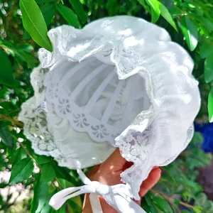 Close-up of white lace baby bonnet with delicate embroidery and ribbon ties