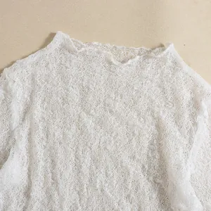Close-up of intricate white lace embroidery and hollow knit texture on the fabric