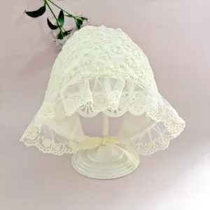 Detail of baby lace bonnet with floral embroidery and ruffle trim on display