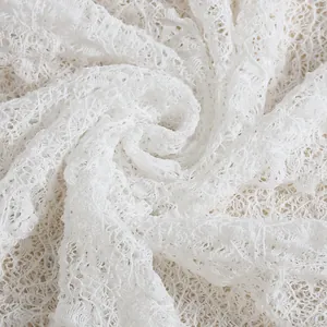 Close-up of white floral lace fabric with intricate embroidery and hollow out details