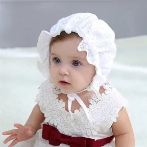 Close-up of white lace baby bonnet with wave edges and delicate floral embroidery