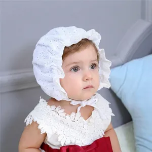 Close-up of baby white lace bonnet and dress with a vibrant red silk bow detail