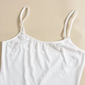 Detailed view of white camisole top featuring thin straps and pleated neckline