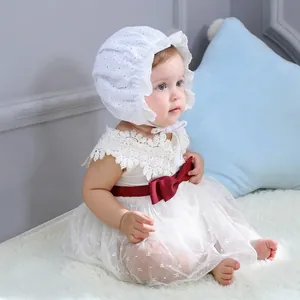 Detail of baby girl lace dress with burgundy bow and ruffled embroidery bonnet