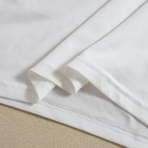 Detail view of white lace dress hem with fine fabric texture and double stitching