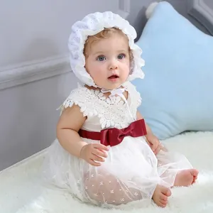 Detail of white lace baby princess dress with large red bow and matching bonnet