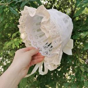 Detail of baby lace bonnet featuring delicate floral ruffles and a silk butterfly bow