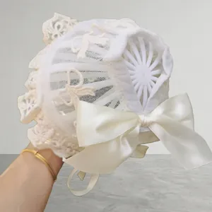 Close-up of baby lace bonnet featuring delicate butterfly embroidery and satin bow