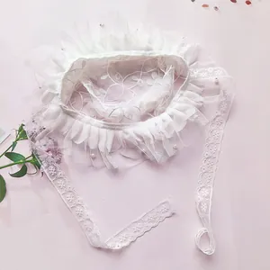 Close-up of white lace baby bonnet with floral embroidery and pearl accents