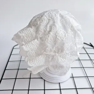 Detailed view of white floral embroidery and wavy lace trim on baby bonnet