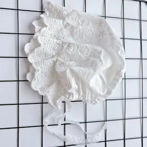 Detailed embroidery and lace edges of white cotton palace style baby bonnet