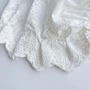 Detailed close-up of delicate white floral lace embroidery and scalloped edges