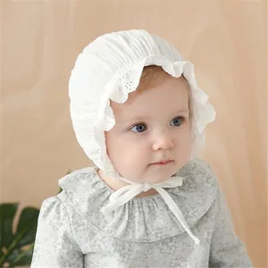 Detail of white cotton lace baby bonnet with embroidered ruffles and chin tie