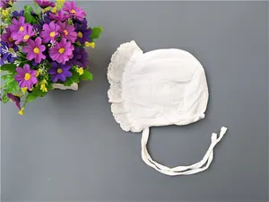 Detailed close-up of white baby bonnet with delicate lace embroidery and ties