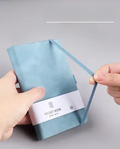 Detail showing elastic strap closure on light blue A6 textured leather notebook