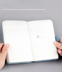 Detail view of small blue portable notebook showing 9mm ruled pages and sewn binding