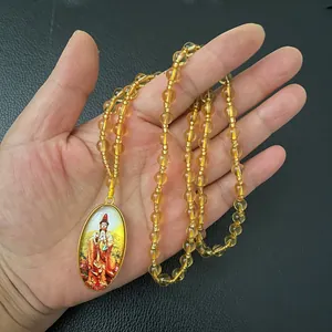 Detailed close-up of oval Guanyin pendant with yellow beads and golden frame