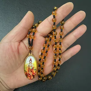Detail view of Guanyin Buddha pendant necklace with amber beads held in hand