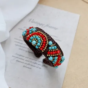 Detail of bohemian woven bracelet with red and turquoise beads on vintage card