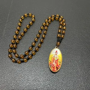 Macro shot of Buddhist necklace with amber beads and oval Bodhisattva deity pendant