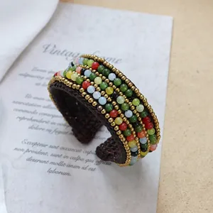 Detailed close-up of wide bohemian handmade braided cuff with colorful stone beads