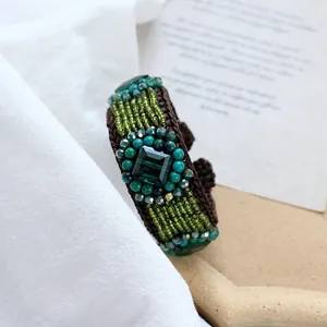 Macro shot of handmade bohemian woven bracelet with green stones and vintage beads