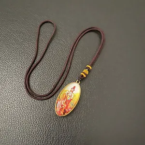 Oval religious pendant necklace with golden frame and Buddhist imagery on black leather