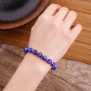 Detailed close-up of handmade evil eye beaded bracelet on a wrist with natural props