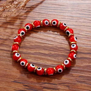 Macro detail of red Evil Eye beaded bracelet with gold spacers on wood texture
