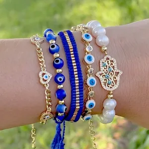 Five-piece evil eye bead bracelet set with Hamsa hand and heart charms on a female wrist