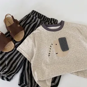 Flat lay of beige elephant print t-shirt and striped pants with brown sandals