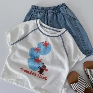 Flat lay of kids summer set with white graphic t-shirt and blue denim shorts