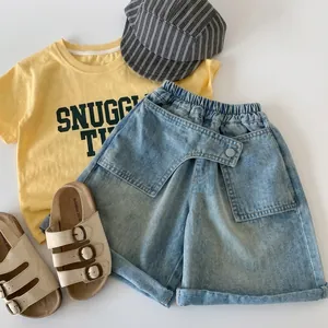 Flat lay of yellow t-shirt with snuggly time text and blue denim shorts set