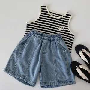 Flat lay of kids striped tank top and denim shorts with sandals on grey background