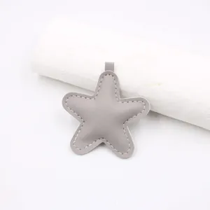 Close-up of grey star leather pendant with white stitching detail and silver ring