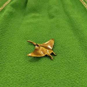 Macro detail of a vintage golden brass manta ray ornament with textured wings