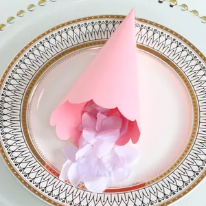 Close-up of pink confetti cone with wavy edges and purple petals on a decorative plate