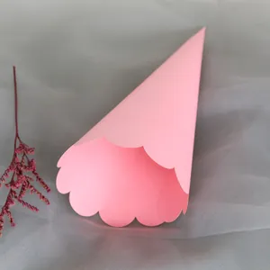 Pink paper cone with scalloped edges for wedding flower petals on grey mesh fabric