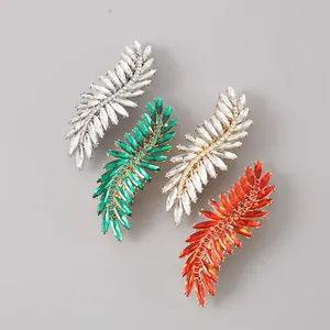 Detailed view of four crystal-encrusted leaf hair clips in various vibrant colors