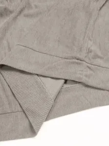 Détail du tissu en velours côtelé taupe avec coutures fines et texture sur le poignet