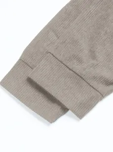 Gros plan du poignet en velours côtelé gris montrant la texture détaillée du tissu rayé