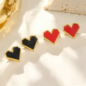Détail de boucles d'oreilles cœur dorées avec incrustations émail rouge et noir