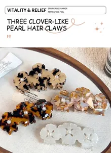 Detail of clover hair claw clip with acetate marbling and pearl accents on white fabric