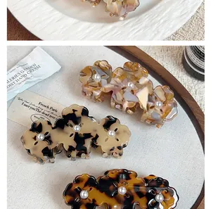 Close-up of acetic acid flower hair claws with marble texture and pearl details