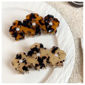 Close-up of tortoise shell and leopard pattern hair claws with pearl flower accents