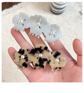 Detail view of acetate clover hair claws with marble textures and pearl accents