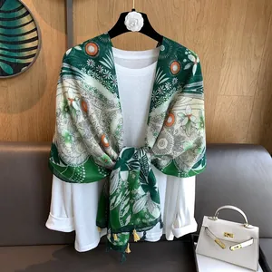 Détail d'une écharpe à fleurs vintage avec glands vert foncé sur fond en bois
