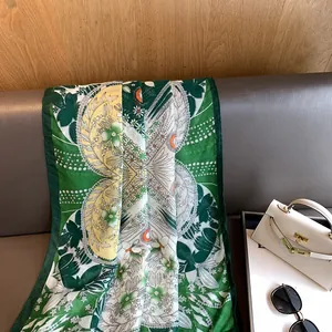 Détail d'un châle en soie floral sur canapé en cuir avec accessoires de voyage